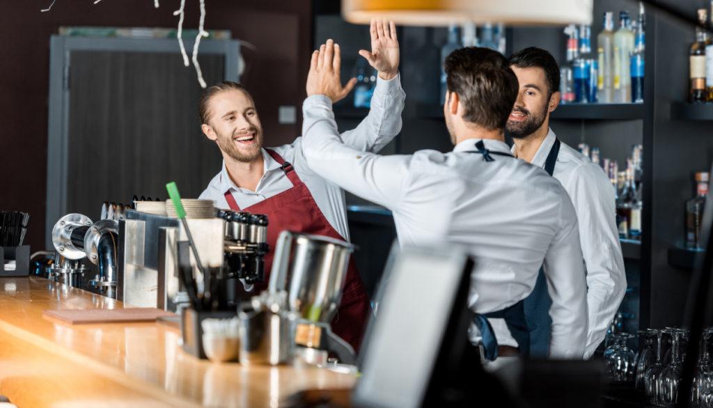 Restaurant team celebrating behind bar