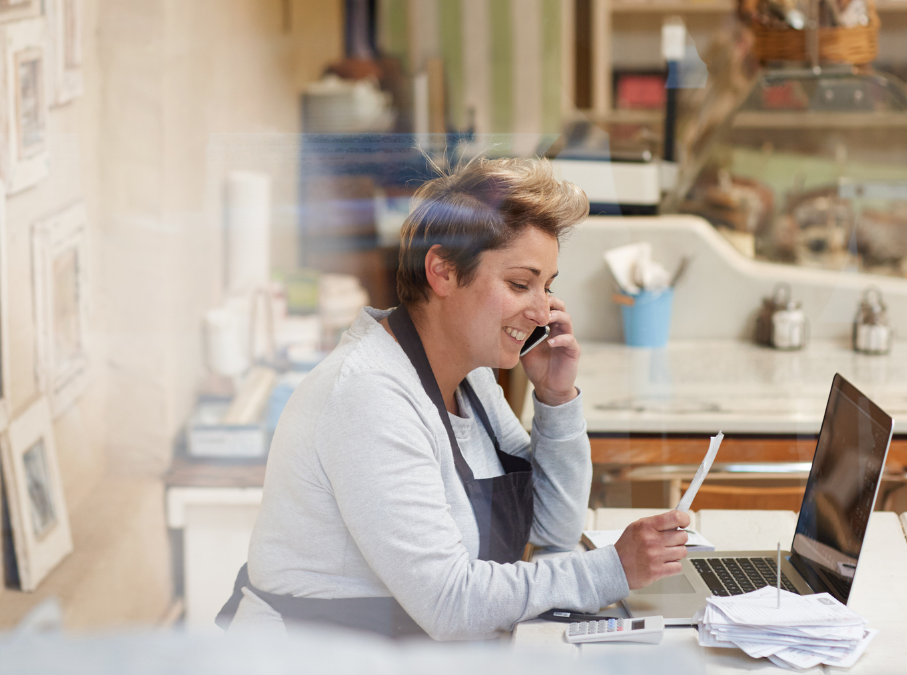 restaurant employee on phone while punching in data to laptop