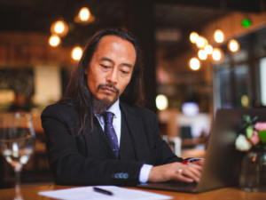 Man in suite on laptop at restaurant dining table