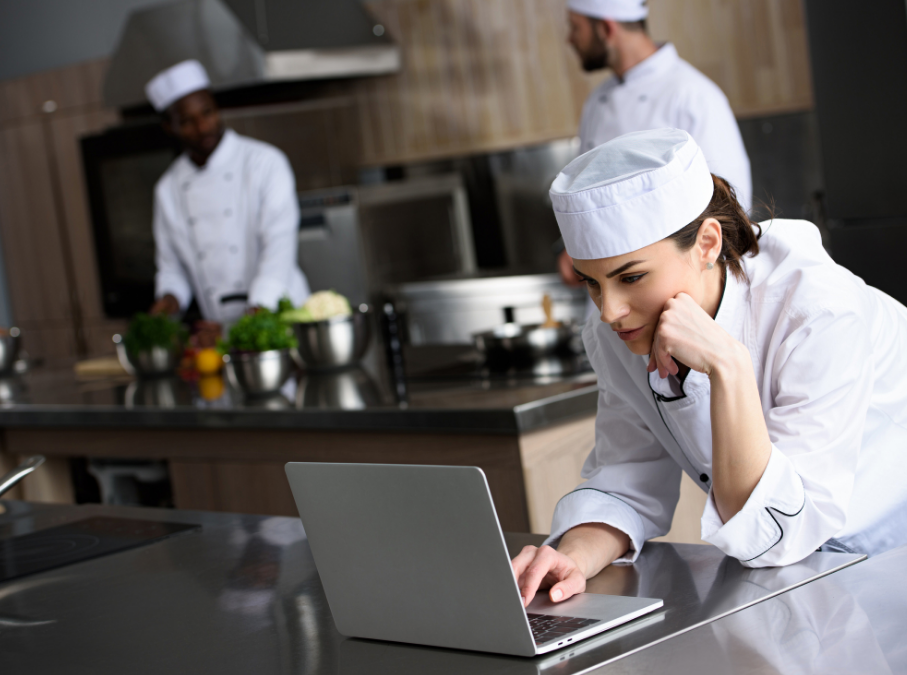 Restaurant chef logging inventory on laptop