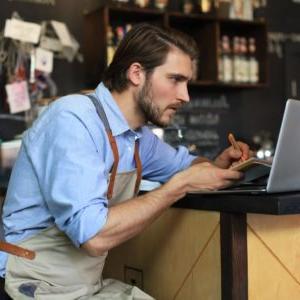 Restaurant operator reviewing report on laptop