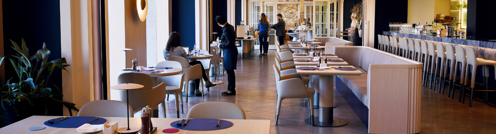 Modern restaurant dining room with patron and server.