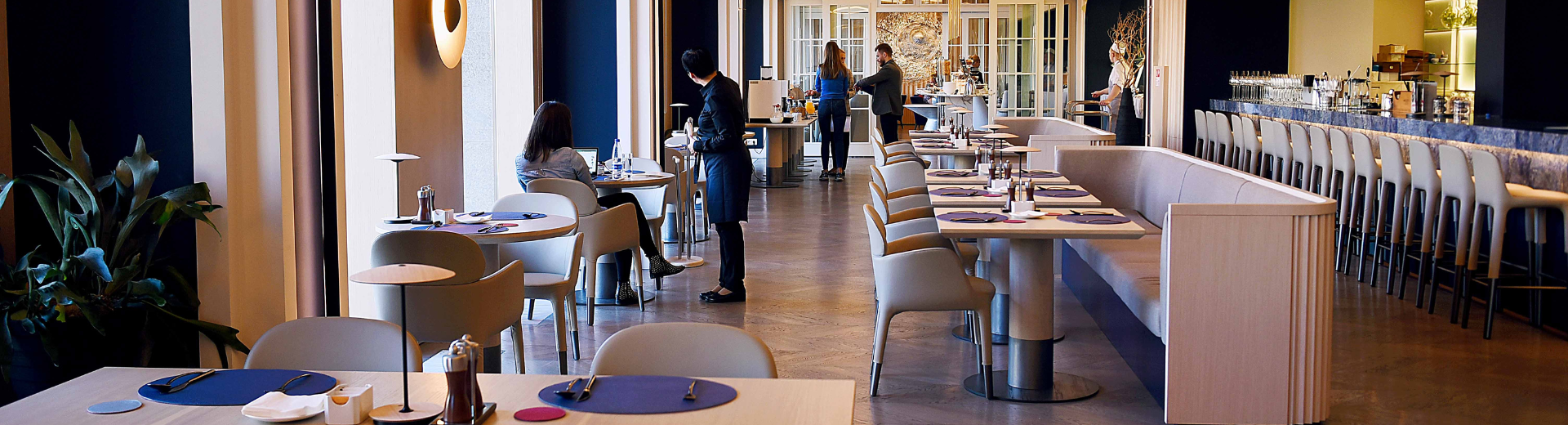 Modern restaurant dining room with patron and server.
