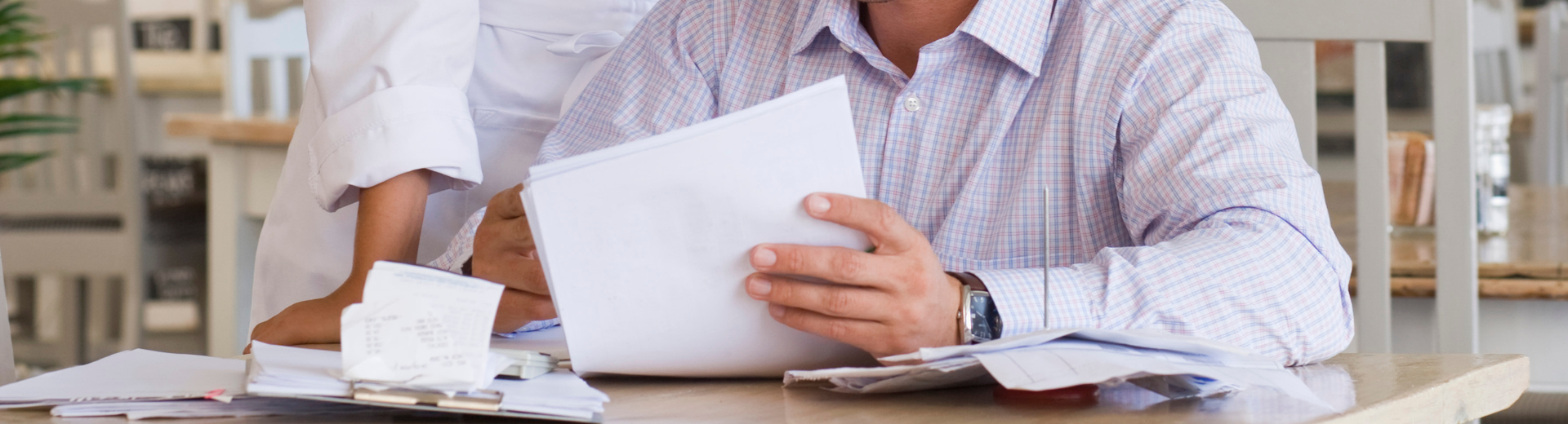 Close up of man with collared shirt looking at tax papers.